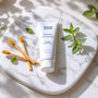 Plan détaillé de bâtons de siwak et dentifrice SiwakSmile posés sur un marbre blanc, décorés de feuilles de menthe et d’eucalyptus pour évoquer pureté et fraîcheur naturelle.