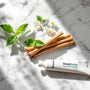 Plan rapproché d’un bâton siwak naturel et d’un dentifrice SiwakSmile posés sur un marbre, entourés de brins de menthe et de feuillages d’eucalyptus dans une ambiance zen.