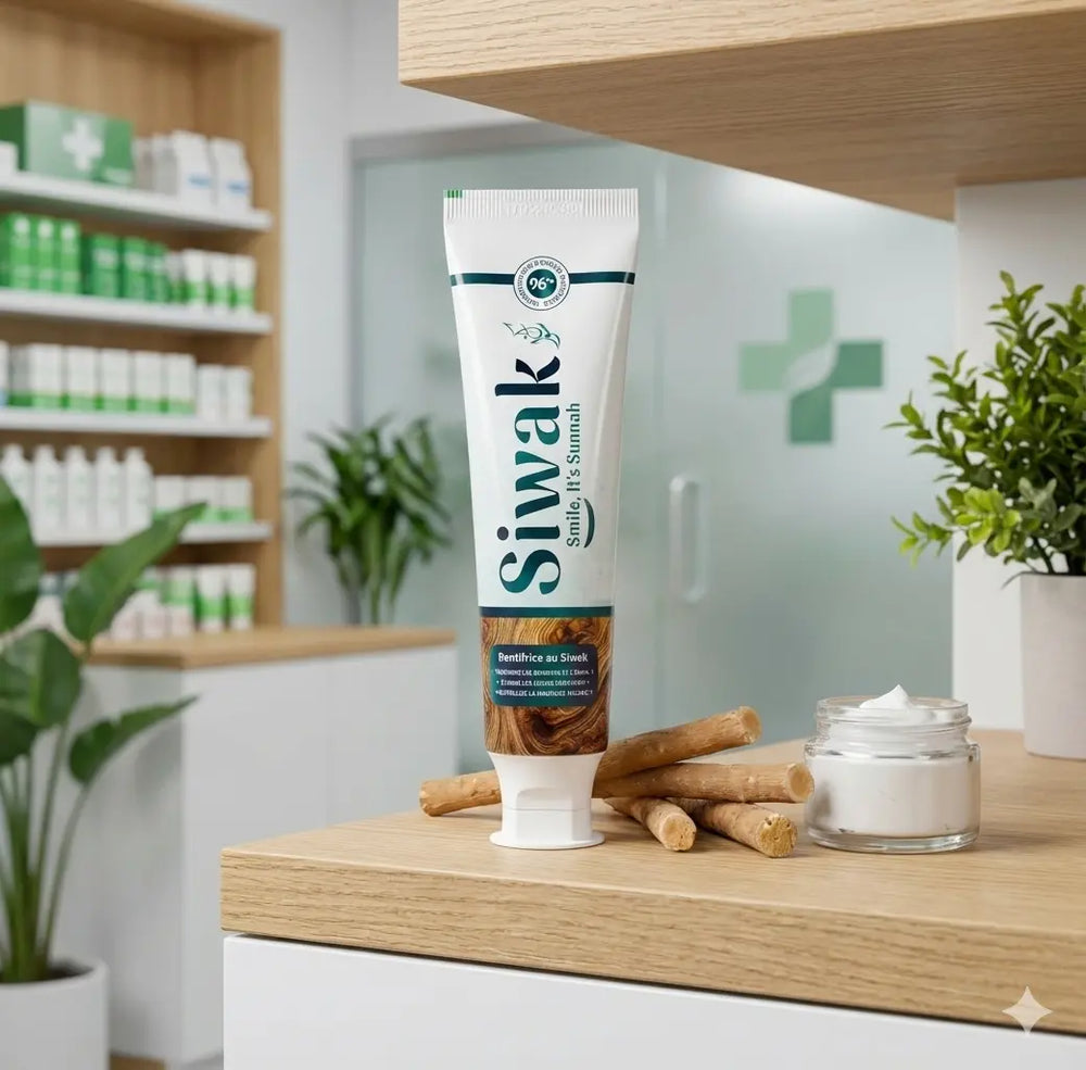 Tube de dentifrice naturel Siwak "Smile, it's Sunnah" posé sur une étagère en bois, entouré de bâtons de siwak bruts et d'un petit pot de pâte, dans un environnement de pharmacie avec une croix verte en arrière-plan.