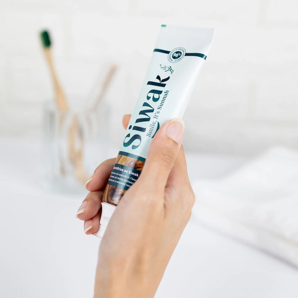 Main tenant dentifrice Siwak dans salle de bain minimaliste - Produit hygiène dentaire halal et bio