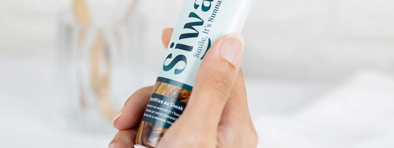 Main tenant dentifrice Siwak dans salle de bain minimaliste - Produit hygiène dentaire halal et bio