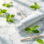 Plan rapproché de bâtons de siwak disposés avec un tube de SiwakSmile sur marbre blanc, entourés de feuilles de menthe, illustrant un moment spa naturel – siwak ou en trouver pour une hygiène buccale pure.