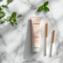 Packshot élégant avec un tube de dentifrice siwak SiwakSmile et des bâtons de siwak posés sur un marbre blanc, entourés de menthe et d’eucalyptus dans une ambiance spa naturelle.